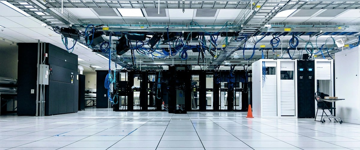 Data center floor with server racks and overhead cabling representing hyperscale and AI data centers