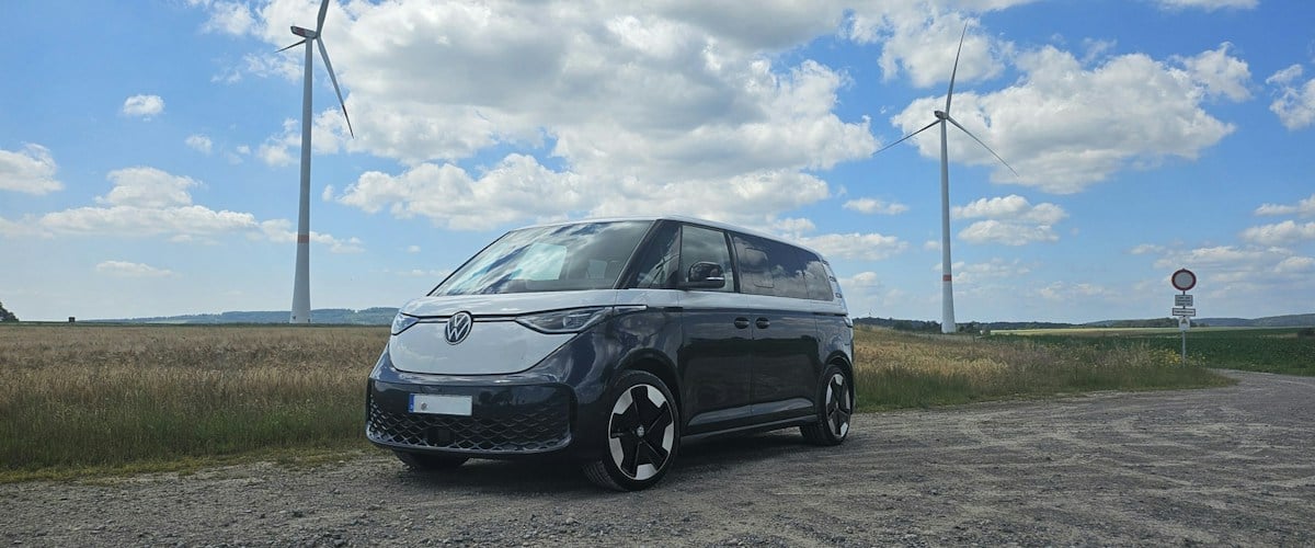 Electric vehicle parked near wind turbines representing EVs and renewable energy